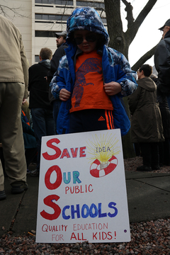 A child stands behind a sign that says 