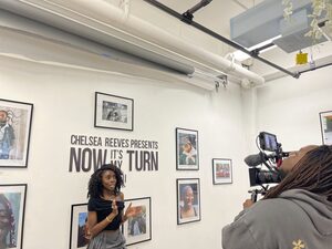 Chelsea Reeves stands in front of her work at her second gallery. More than 80 Syracuse community members attended the event to see her work, titled “Now It’s My Turn Part II.”