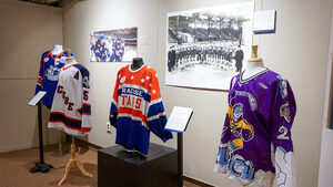 Historically significant Syracuse sports team merchandise lines the walls of the Onondaga Historical Association. Items include different colored jerseys, footballs and photographs. 