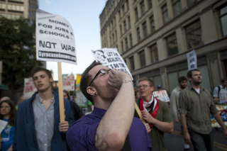 Josh Wilcox, an Occupy supporter from Syracuse, screams chants as members of Occupy Syracuse march through city streets on the movement's one-year anniversary on Monday evening.