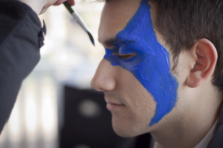 Joshuah Romero, a junior and staff photographer, gets his face painted Michigan colors on Thursday afternoon.