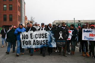 Demonstrators hold multiple signs advocating against domestic violence.