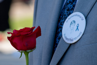 Scholars wear pins depicting the student victim they are tasked with representing throughout remembrance week and the weeks leading up to it. Jared Welch displays his pin on the lapel on his suit jacket as he waits to read his remarks and place his rose. 
